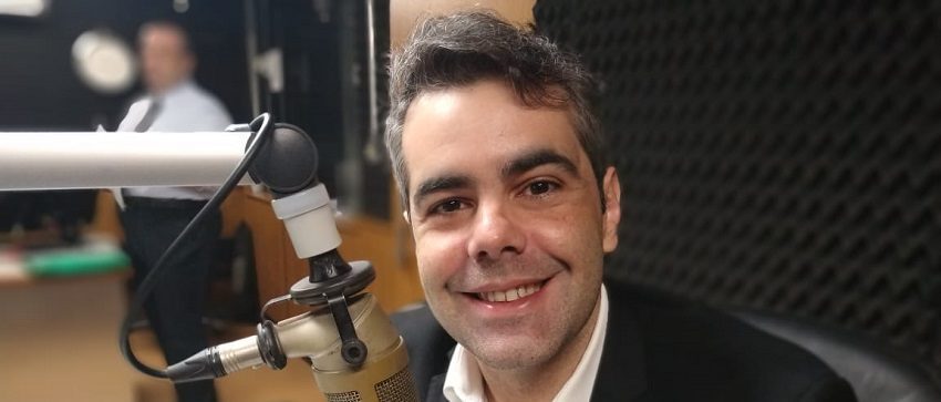 um homem sentado em frente a um microfone em um estúdio de gravação.