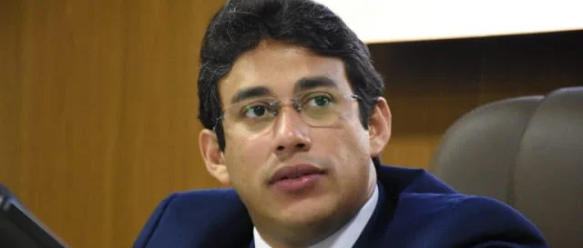 um homem de terno e gravata sentado na frente de um laptop.
